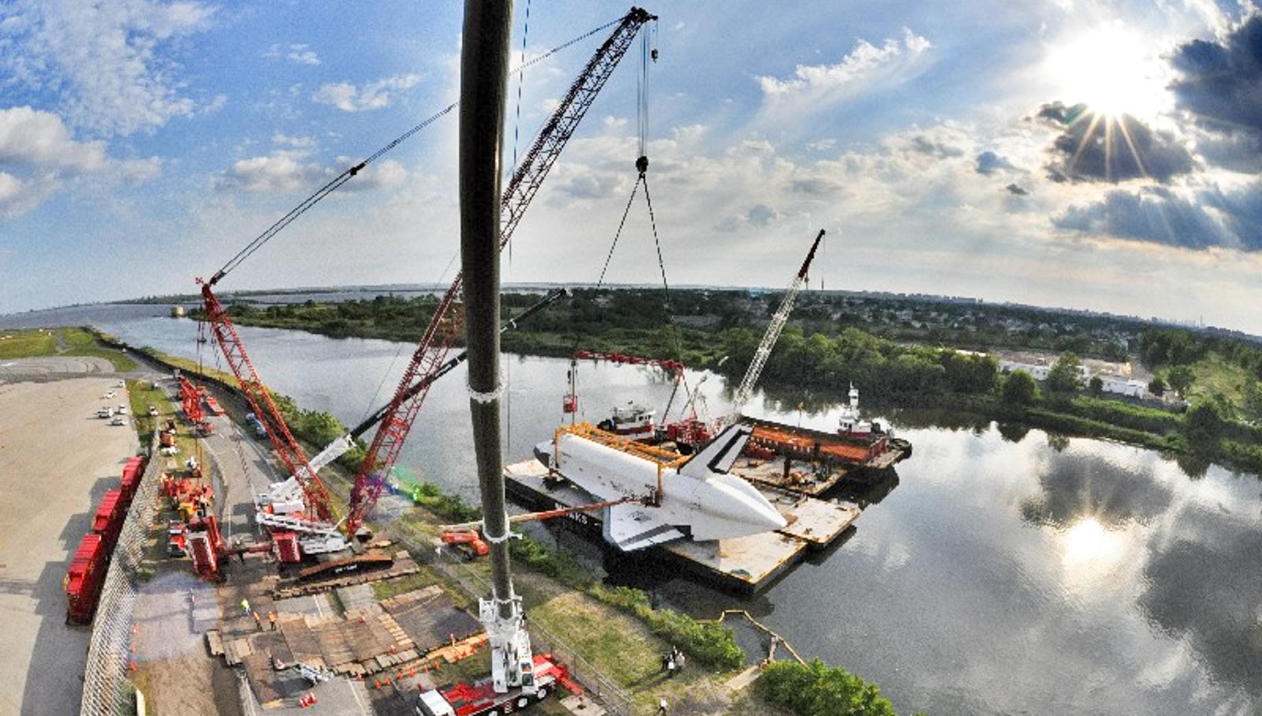 Crane lifting space shuttle onto river platform